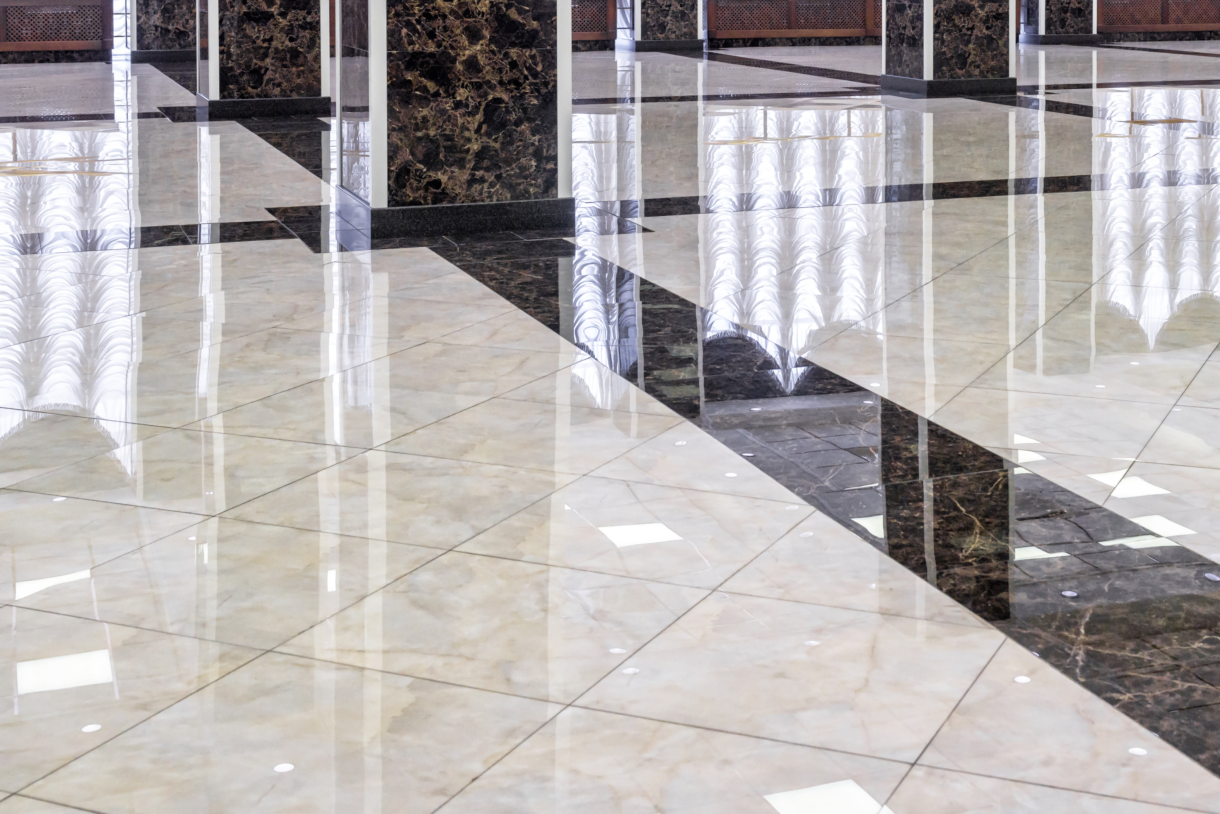 Modern office lobby with polished marble flooring, glass partitions, and dark stone columns